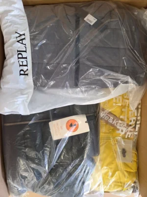The photo shows a package with clothing in the category AJW.